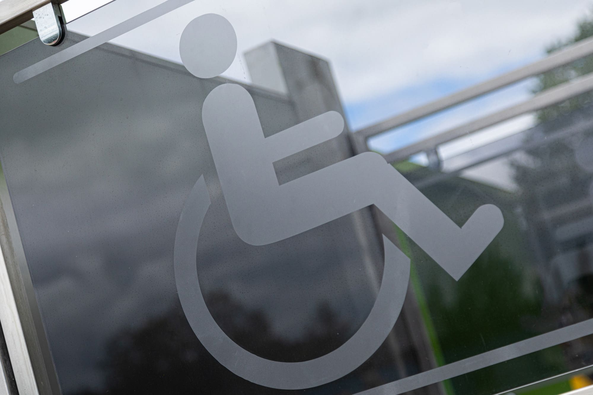 Logo PMR affiché sur une vitre signalant un accès pour personnes à mobilité réduite.